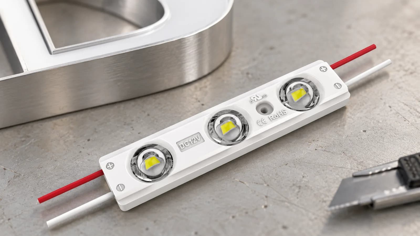 Close-up of a three-lens LED sign module on a fabrication workbench