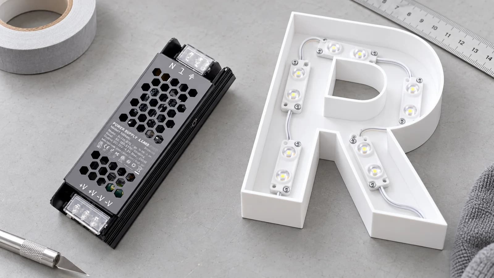 LED driver beside channel-letter components on a fabrication workbench